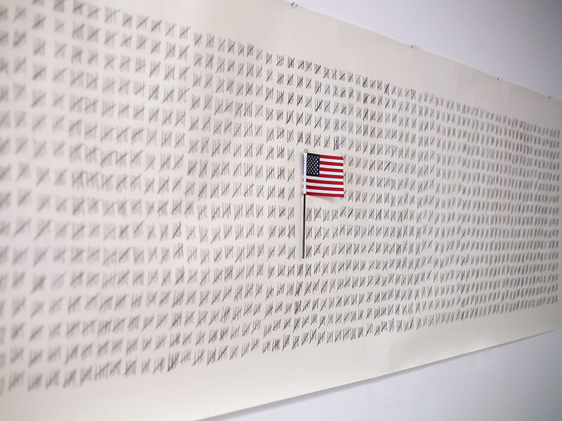 Safwat Saleem, 7,103, 2023. Charcoal on paper roll, American flag from naturalization ceremony. 156 x 38 inches. Courtesy of the artist, Photo: Lisa Olson.